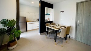Cozinha moderna com armários brancos, uma parede de destaque preta e uma área de jantar com mesa posta para quatro pessoas.
