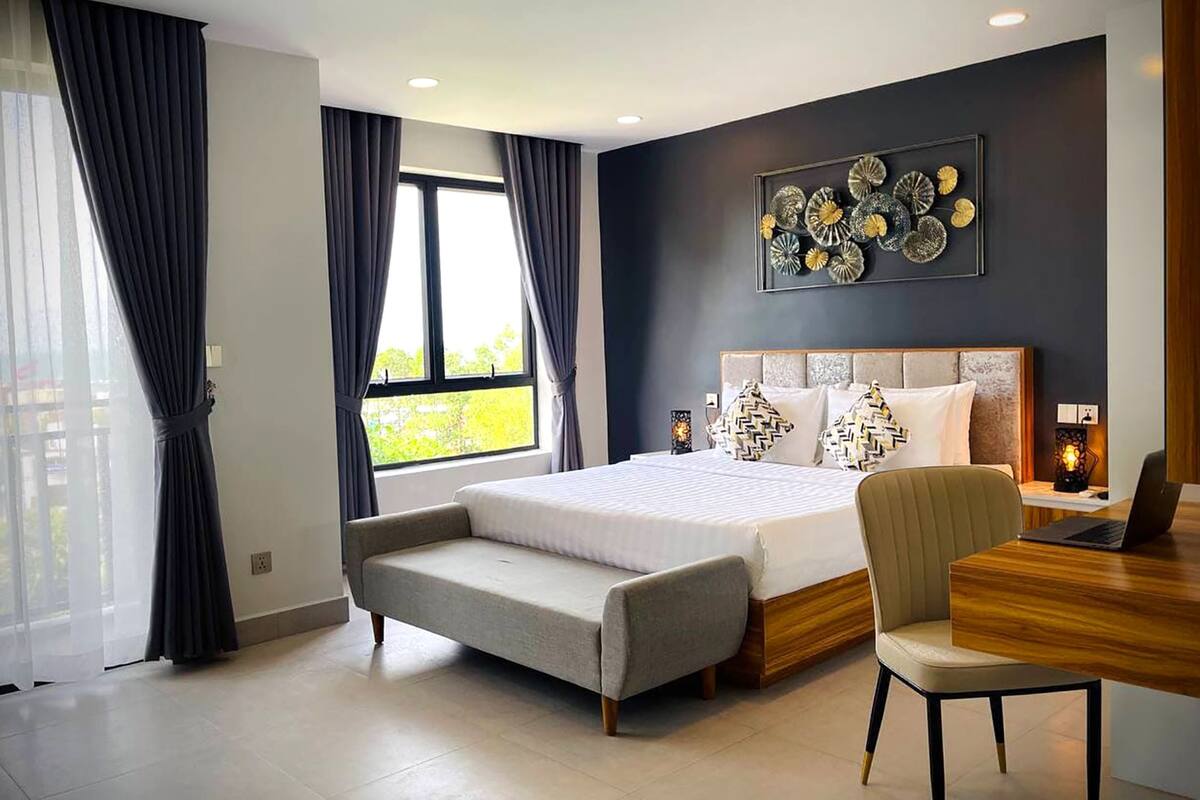 A modern bedroom with a large bed, a desk, and a chair.