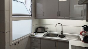 A compact kitchen with grey cabinets, a double sink, and a window. - Horizon Apartment: Large Terrace and Panoramic Ocean View on the Waterfront (Los Cristianos)