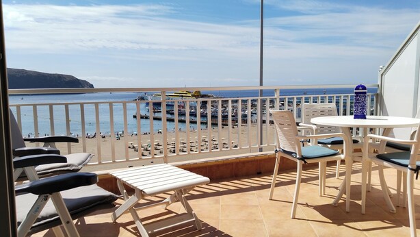 A balcony with a view of the beach, white outdoor furniture, and a table with chairs. - Horizon Apartment: Large Terrace and Panoramic Ocean View on the Waterfront (Los Cristianos)