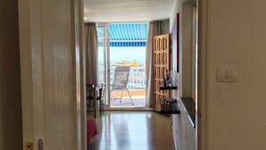 A hallway leading to a balcony with a view of a yellow building. - Horizon Apartment: Large Terrace and Panoramic Ocean View on the Waterfront (Los Cristianos)