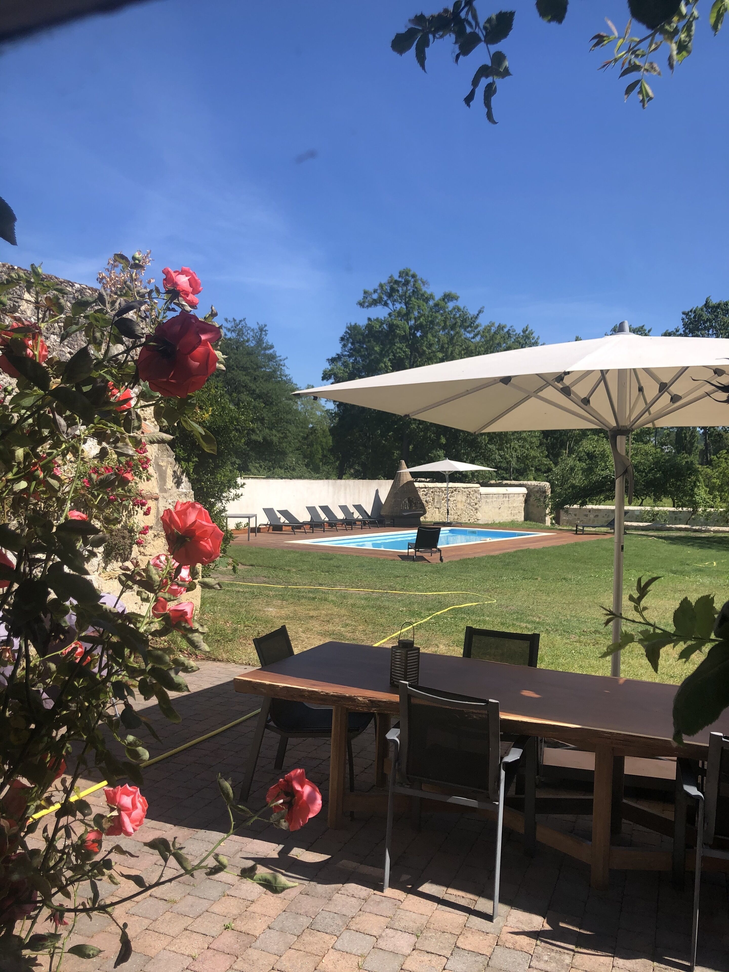 Un patio con mesa y sillas, piscina y una gran sombrilla.