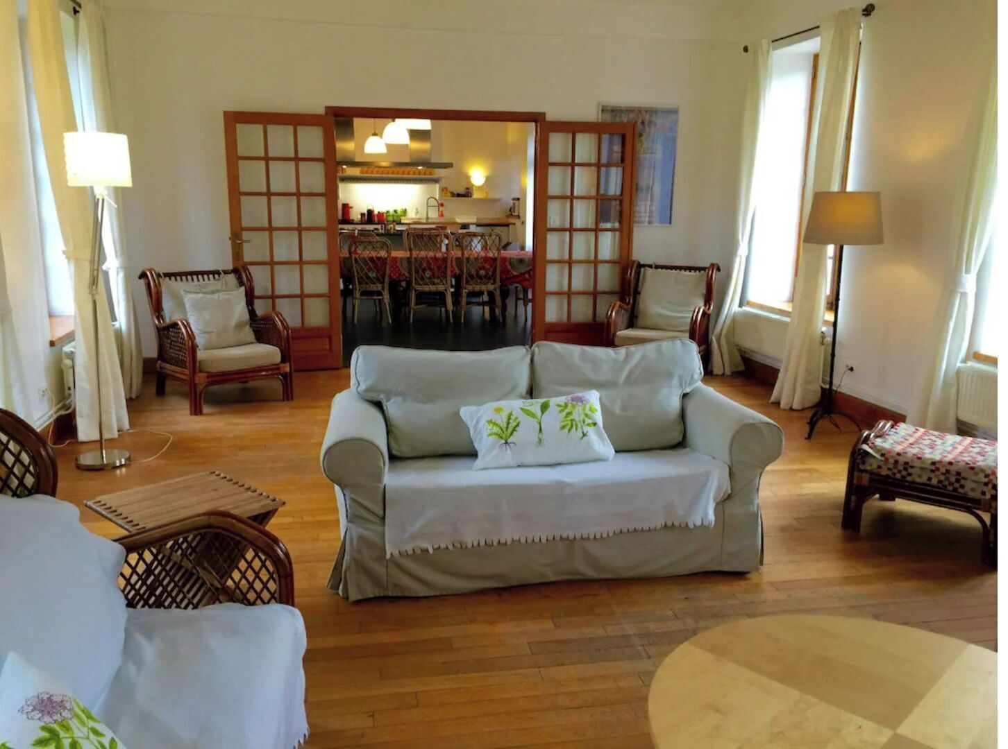 Ein Wohnzimmer mit einer Couch, Stühlen, einem Esstisch und einer Küche im Hintergrund.