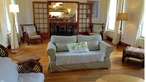 A living room with a sofa, chairs, a dining table, and a kitchen in the background. - Le Presbytère, The Presbytery of Fourdrain (Fourdrain)