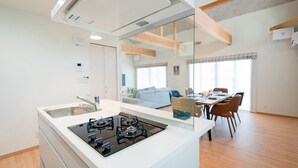 Une cuisine moderne équipée d’une cuisinière à gaz, d’un évier et d’un coin repas avec une table et des chaises.