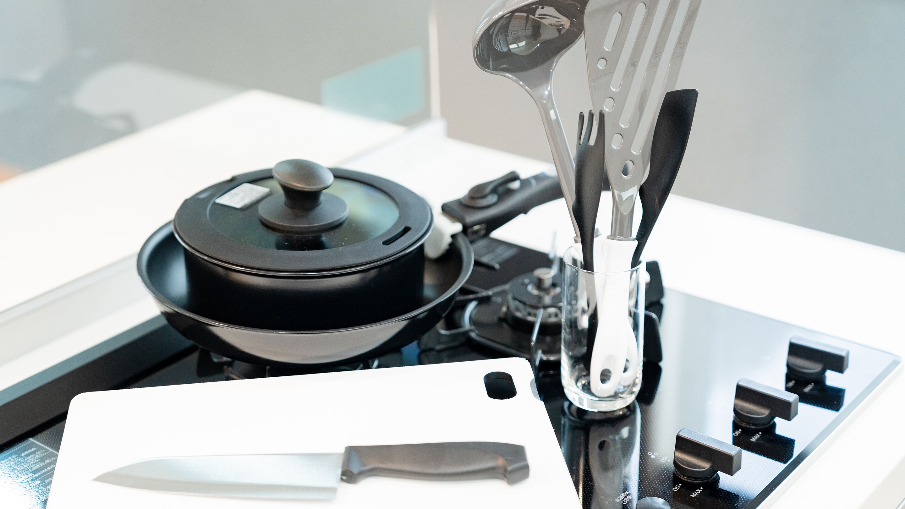 A kitchen with a stove, a pot, a knife, and a utensil holder.