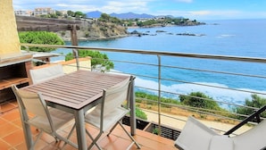 Un balcón con mesa y sillas que da a vistas de la costa.