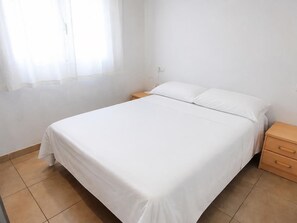 A bedroom with a bed, nightstands, and a window with sheer curtains. - Apartment with terrace, parking and pets welcome in Llançà (Llançà)
