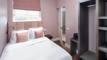 A bedroom with a bed, a bedside table, a wardrobe, and a window with a view.