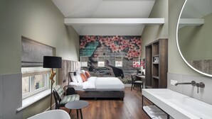 A modern bedroom with a large bed, a desk, a chair, a round mirror, and a bathtub. - Boutique Hotel Brasa Beemster (Middenbeemster)