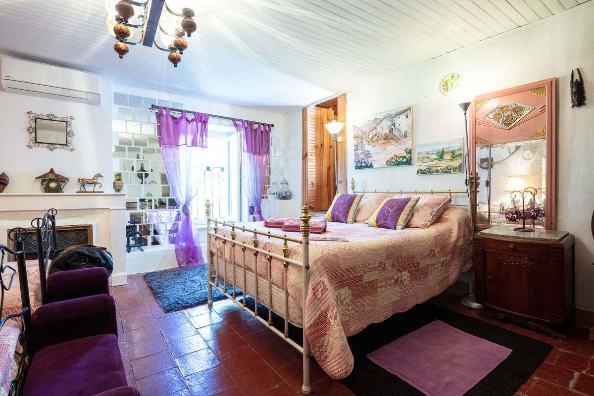 A bedroom with a bed, a dresser, a mirror, and a chandelier.