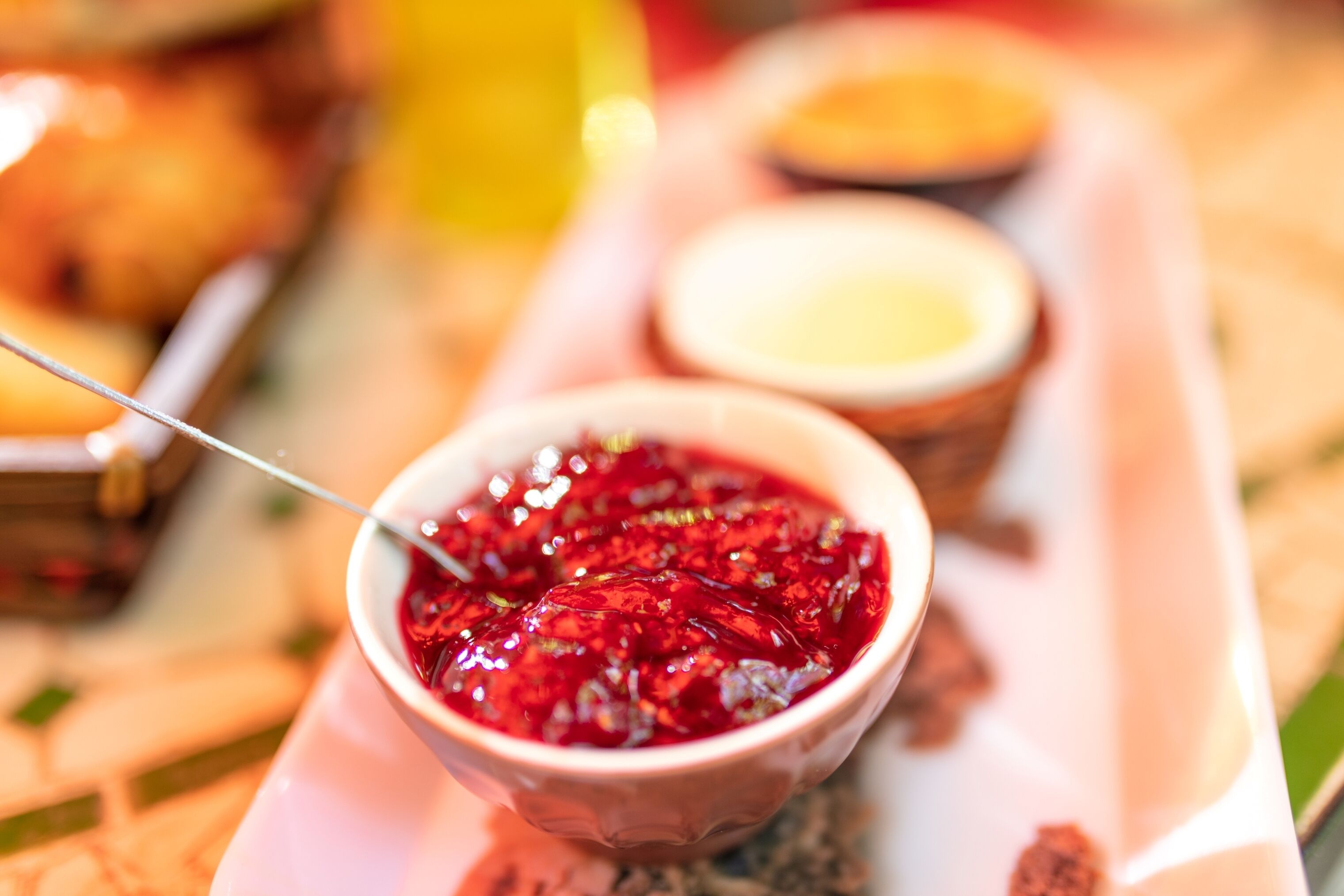 Un vassoio con una ciotola contenente cibo rosso, gelatinoso e un cucchiaio.