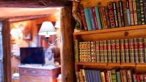A wooden bookshelf filled with books, a lamp, and a television in a cozy room.