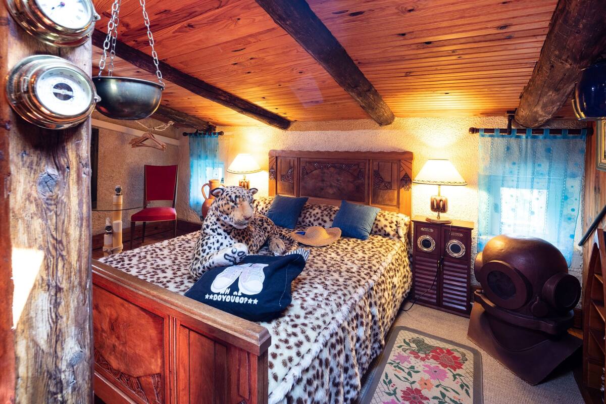 A cozy room with a bed, a leopard print blanket, a wooden headboard, and a vintage radio.