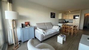 Un salon moderne avec un canapé, une table à manger et une cuisine en arrière-plan.