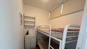 Une chambre avec un lit superposé, un bureau et des étagères.