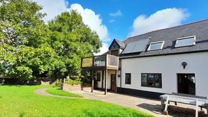 A two-story house with a balcony, a paved driveway, and a grassy yard. - Spacious Converted Barn on a Flower Farm, Devon Countryside, Family Friendly (Kentisbeare)