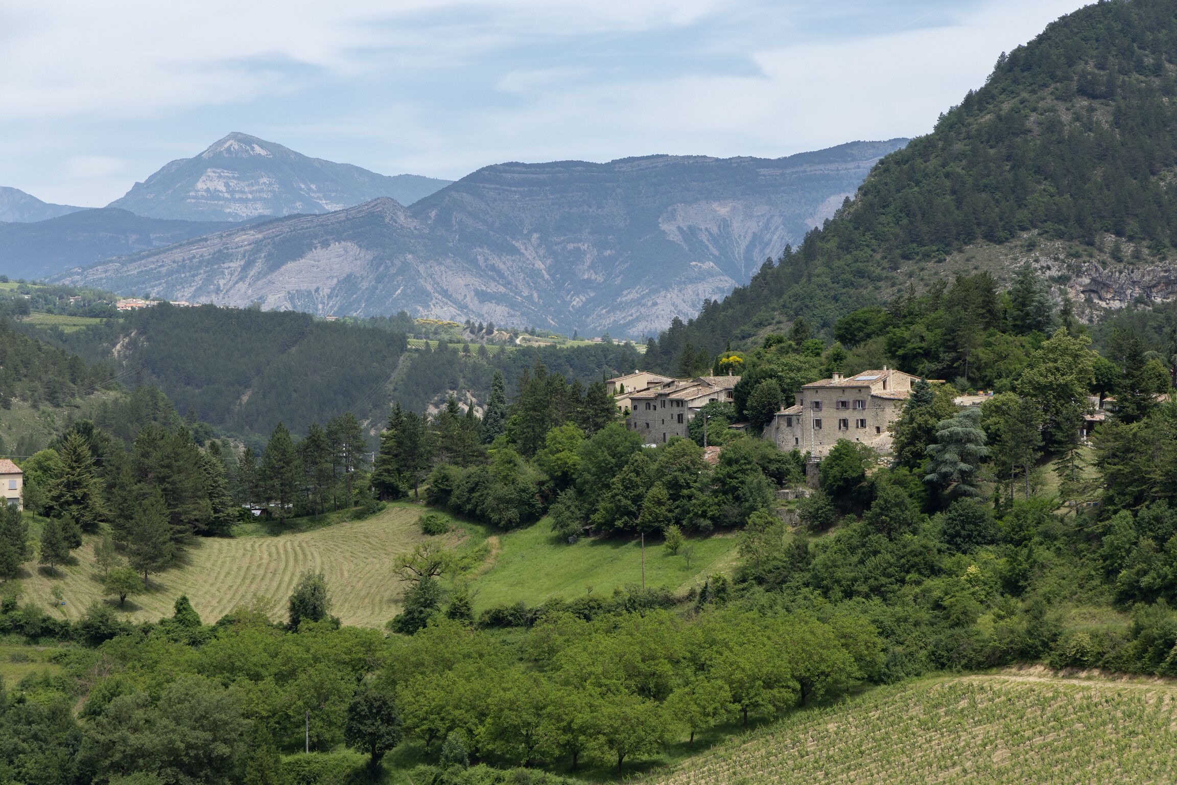 Eine gebirgige Landschaft mit einem Gebäude, umgeben von Grün und Bäumen.