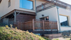 Una casa de dos pisos con un balcón, un ventanal grande y una valla de madera.