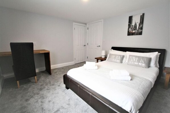 A bedroom with a bed, a desk, and a chair.