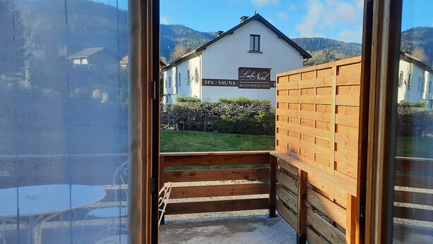 Blick aus einem Zimmer auf eine Wellness- und Saunalandschaft mit Holzzaun und Schild mit angebotenen Leistungen.