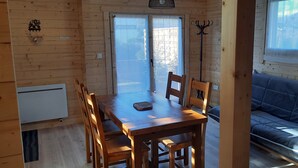 Ein Holzinnenraum mit einem Esstisch und Stühlen, einem Sofa und einem Fenster mit Blick.