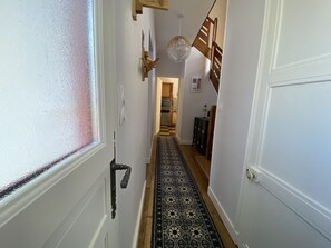 A hallway with a patterned rug, a wooden door, and a staircase leading to another room. - CHARMING GITE IN THE MARAIS POITEVIN (Magné)