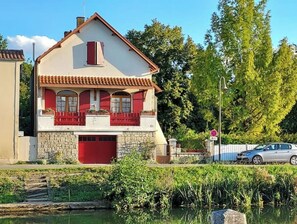 A two-story house with a red door and windows, a stone base, and a tiled roof. - CHARMING GITE IN THE MARAIS POITEVIN (Magné)