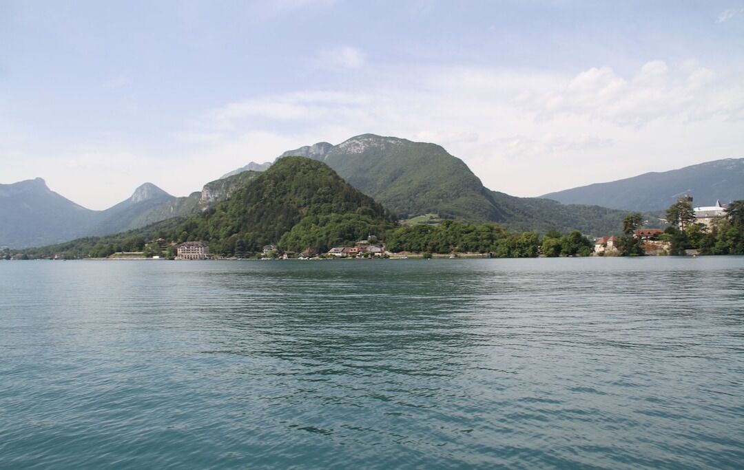 A lake with a mountain in the background and buildings along the shore.
