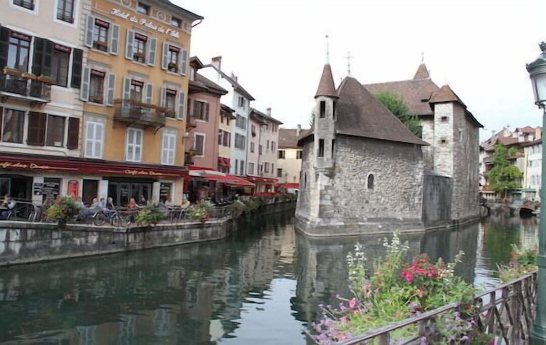 A canal with a stone building and a restaurant with outdoor seating.