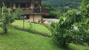 Ein Haus mit Ziegeldach, einem Balkon mit Blumenkästen und einem üppigen Garten.