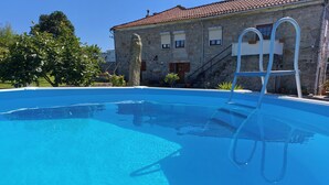 Una piscina cristallina blu con una scala, circondata da edifici in pietra e vegetazione.