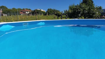 Una piscina azul cristalina con un borde sencillo, rodeada por una valla y árboles.