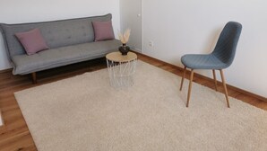 A living room with a grey sofa, a round coffee table, and a blue chair.