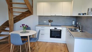 A modern kitchen with white cabinets, a built-in oven, and a wooden staircase.