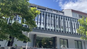 Een modern hotel met een stenen gevel, grote ramen en een trap naar de ingang.