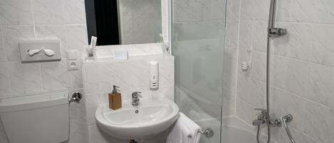 Een moderne badkamer met een douchecabine van glas, een wit wastafelmeubel en een toilet.