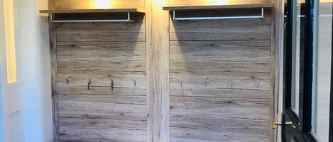 A walk-in closet with wooden paneling and a bench.