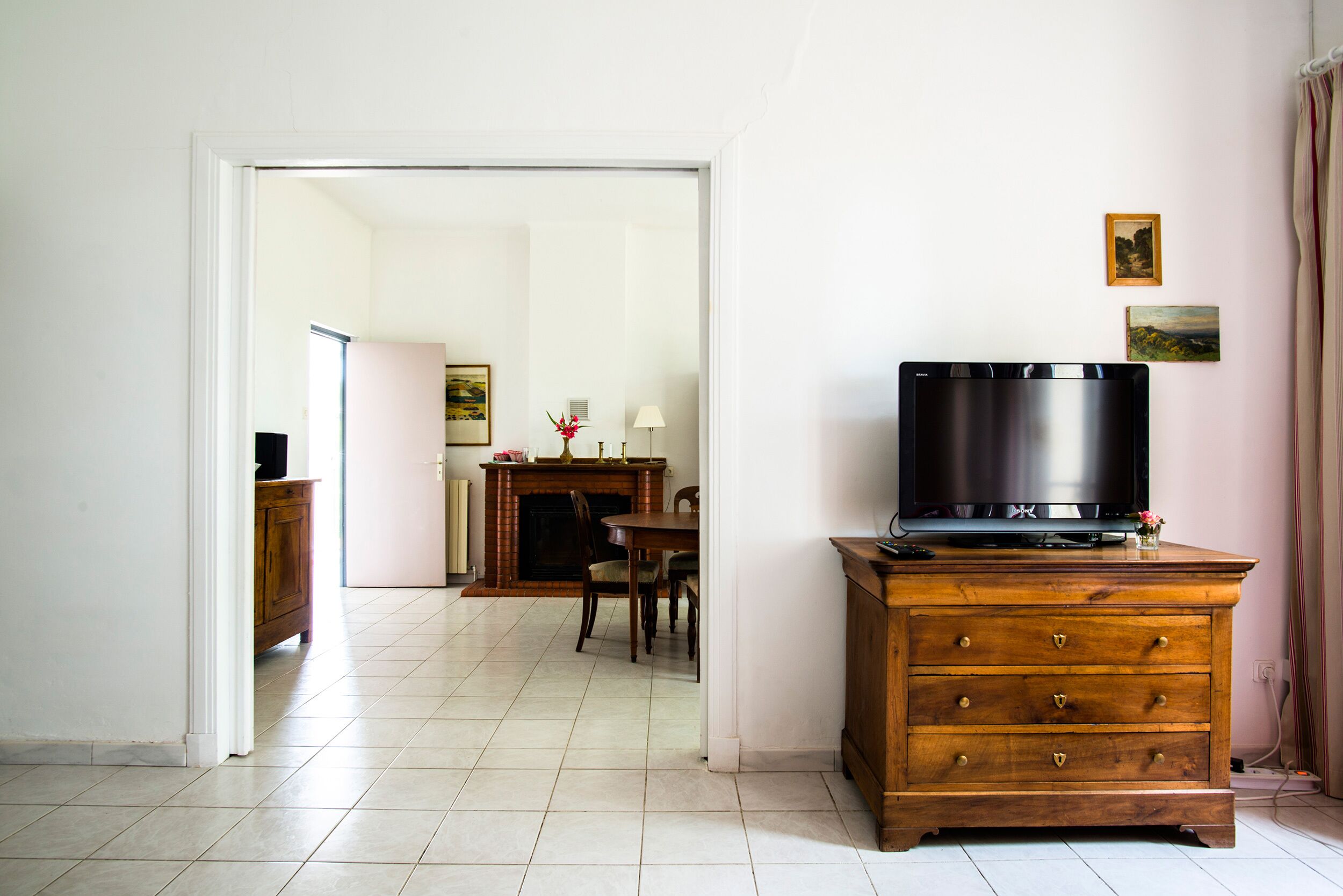 Ein Zimmer mit einem Holzkapfen, einem Flachbildfernseher, einem Esstisch mit Stühlen und einem Kamin.
