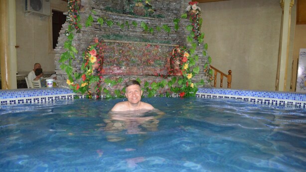 En mand i en swimmingpool med en dekorativ væg i baggrunden.