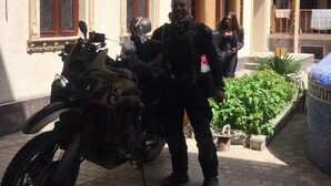 En bygning med balkon, motorcykel og en person der står.