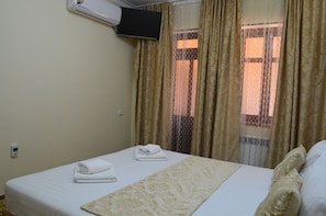 Ein Hotelzimmer mit Bett, Wandfernseher und einem Vorhangfenster.