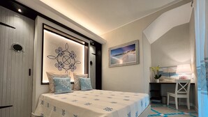 A bedroom with a bed, a desk, and a chair. - Suite Villa Domos & SPA (Porto Pino)