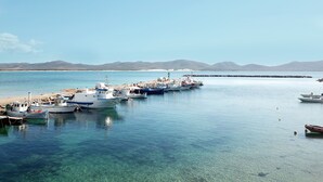A marina with several boats docked, clear blue water, and distant mountains. - Suite Villa Domos & SPA (Porto Pino)