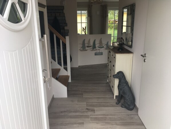 A staircase leading to a landing with a dog sculpture, a white door, and a view of the outdoors through a window.