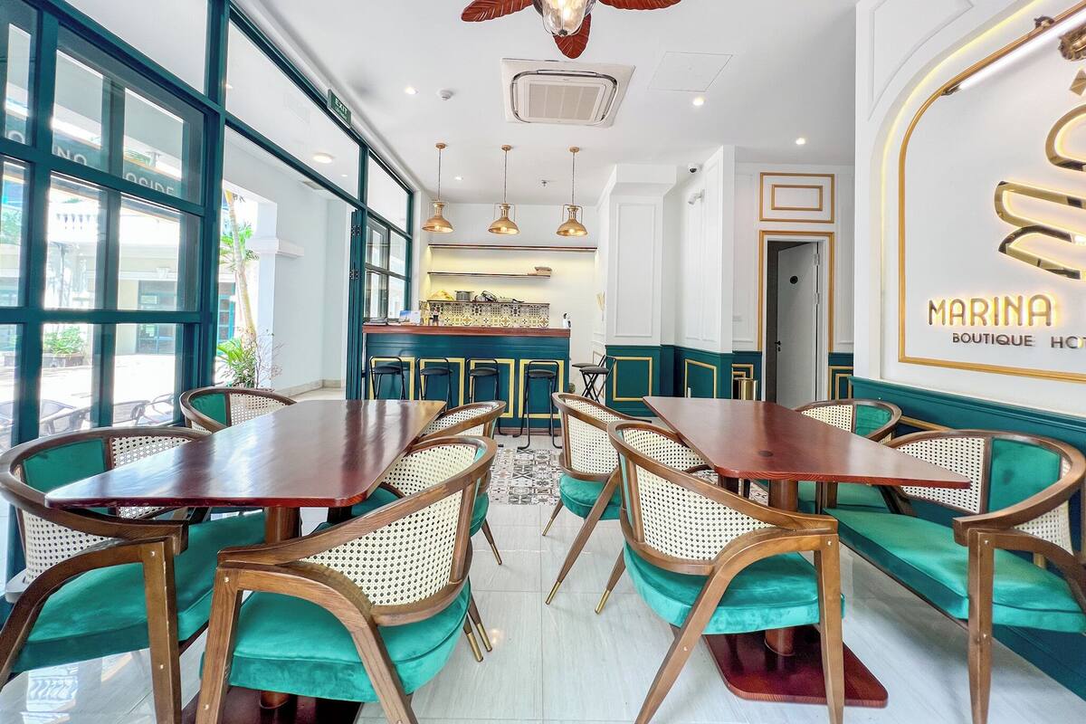 A restaurant with a modern interior, featuring wooden tables and chairs, a bar area, and large windows providing natural light.