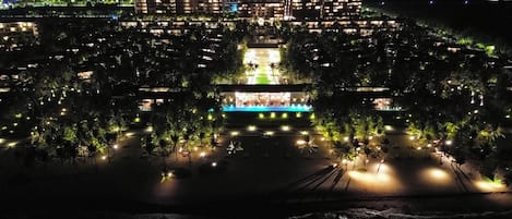 A large hotel with multiple floors, a central courtyard with a pool, and surrounding trees.