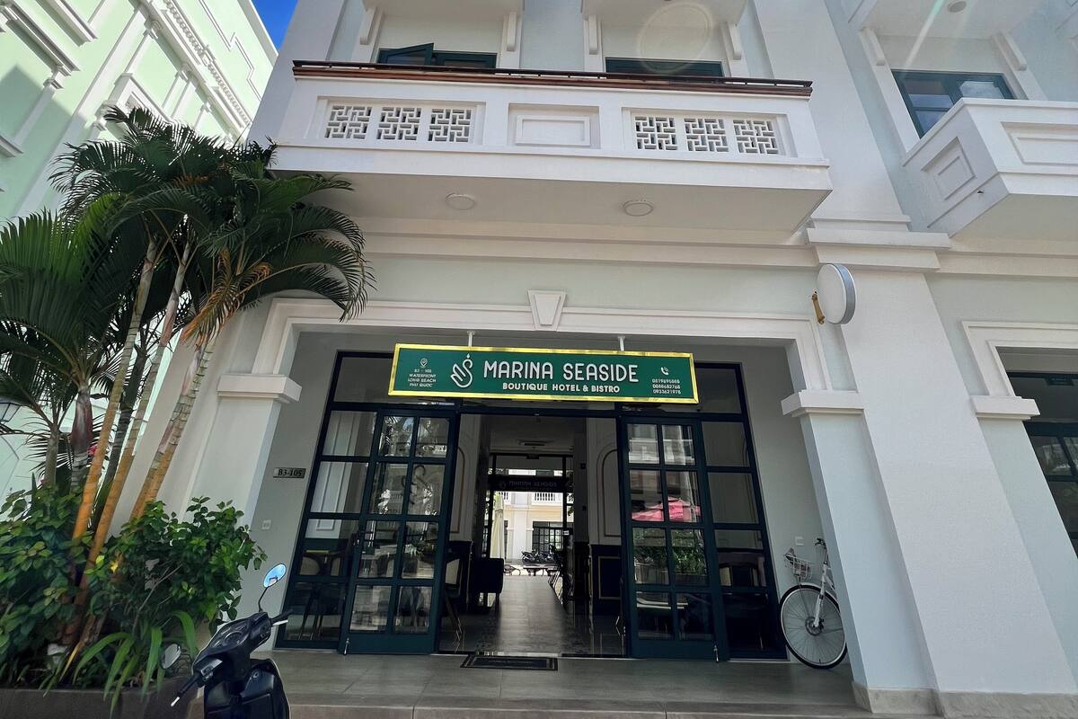 A multi-story building with a sign reading "MARINA SEASIDE BOUTIQUE HOTEL & BISTRO".