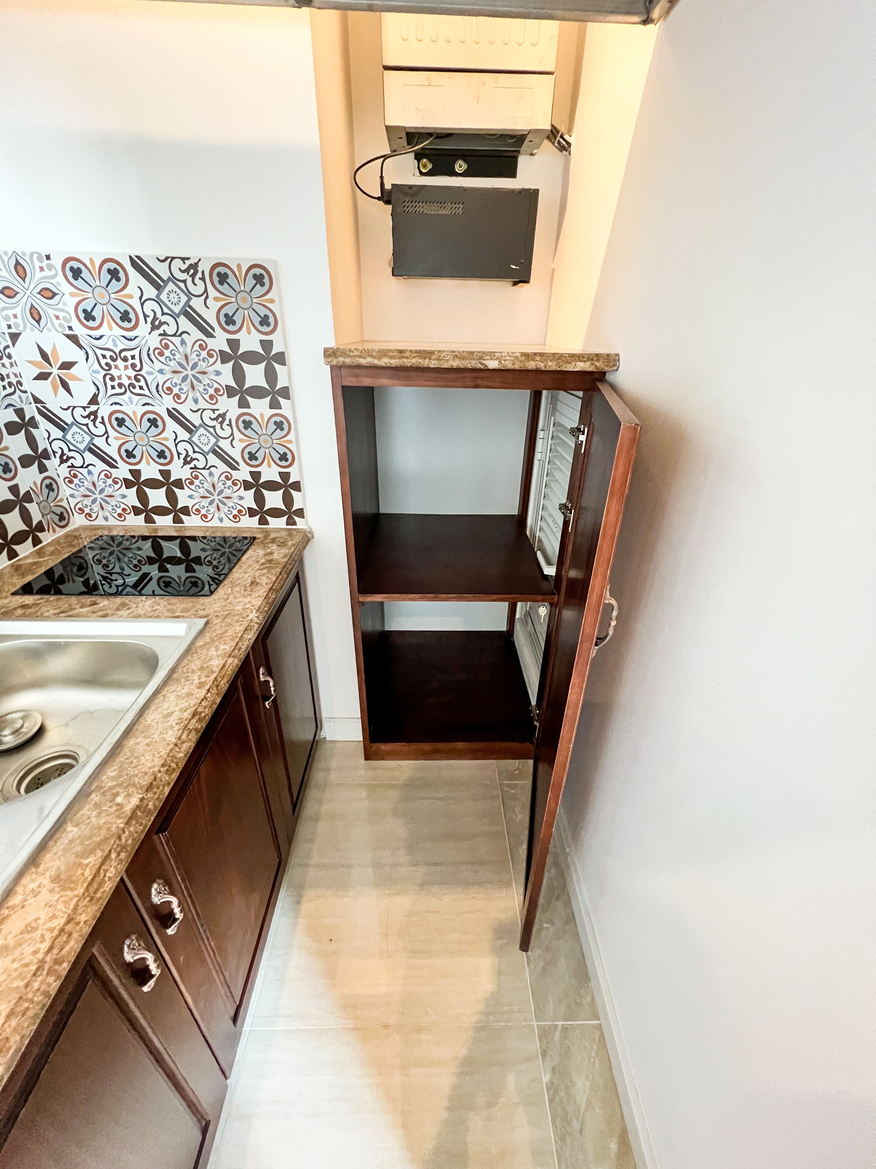 A compact kitchen with a sink, a patterned backsplash, and a built-in oven.