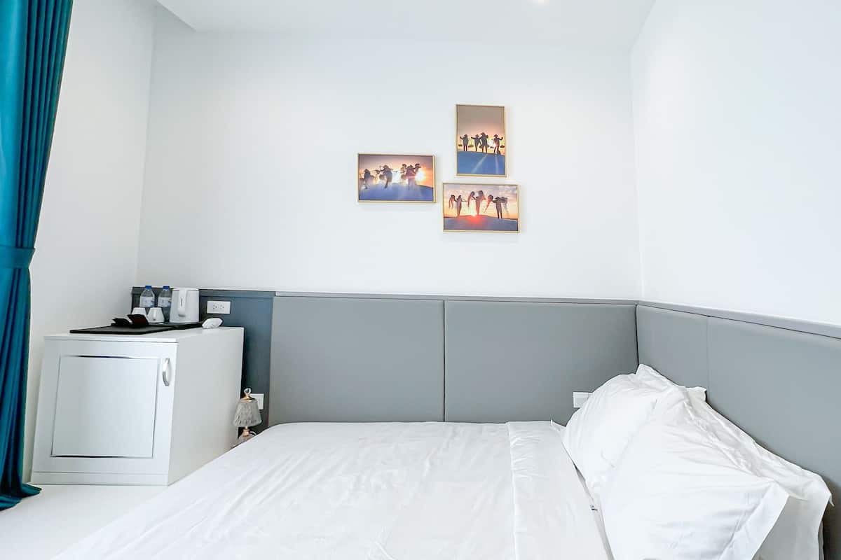A modern hotel room with a large bed, a small bedside table, and a wall-mounted TV.